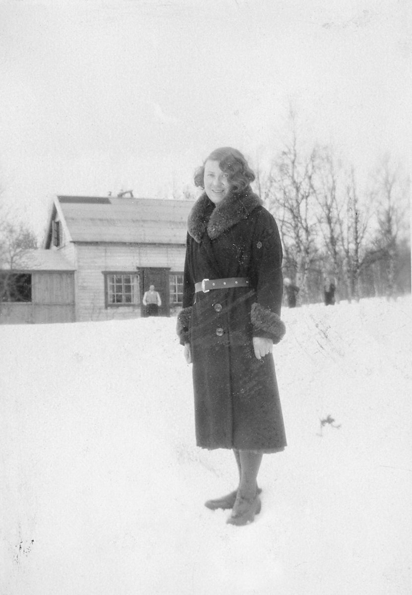 Kvinne fotografert vinterstid, med et hus i bakgrunnen.