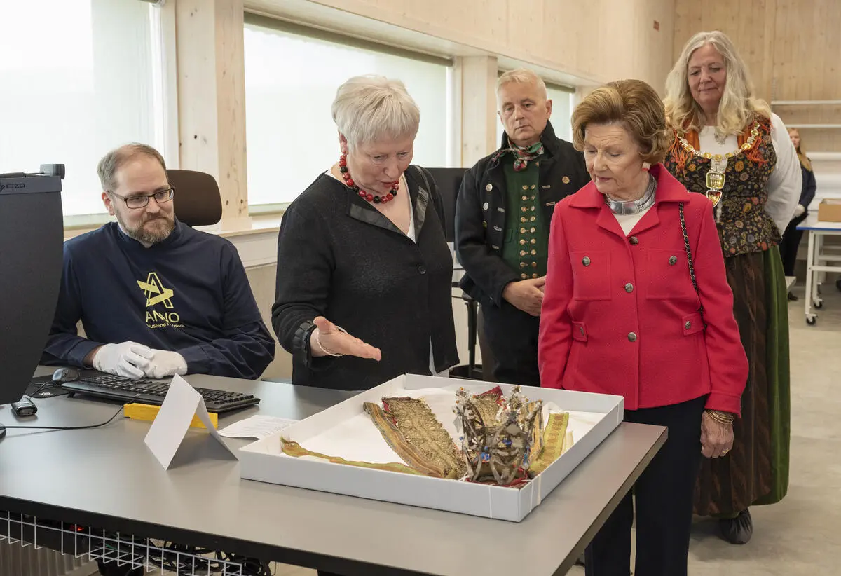 Dronning Sonja ser på en brudekrone fra Kvikne fra ca. 1850. Johnny Thorkildsen og gjenstandskonservator Vigdis Vingelsgaard orienterer Dronning Sonja om brudekrona og faglig arbeid ved bevaringssenteret.