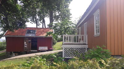 Et gult og et rødt trehus. Det er sommer og grønt. Solen skinner. Huset er Munchs hus i Åsgårdstrand.