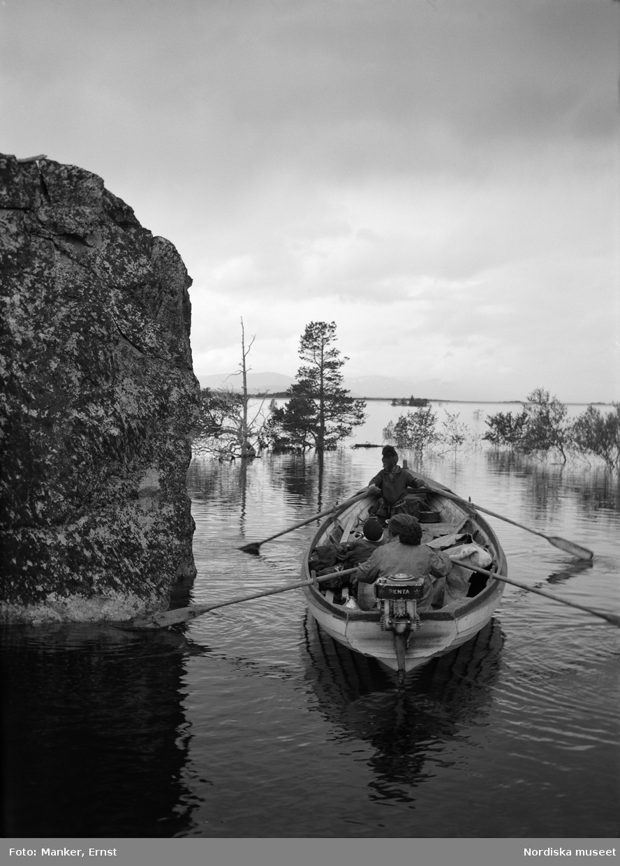 Män i roddbåt Akkajaure vid ön Vuoksanjarka, Gällivare socken, Sörkaitums sameby. Vid klippnjallan efter uppdämningen. Valkeapää från Änonjalme med sin båt. (infl. karesuandosame).