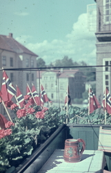 Balkong pyntet med blomster og flagg under feiringen av frig