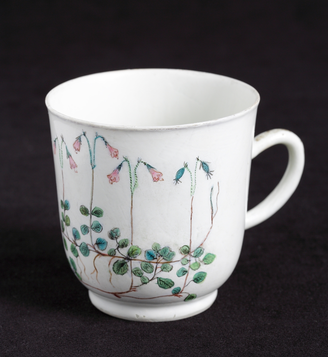 Kaffekopp med dekor av blommande linnéor i rosa och gröna nyanser runt om.
Tillhörande tefat finns.

Inskrivet i huvudkatalog 1935.