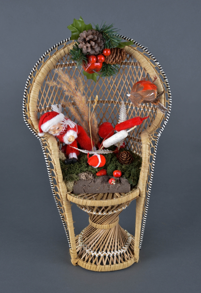 Flettet strå stol med juledekor av blant annet nisse, kongler og mose.