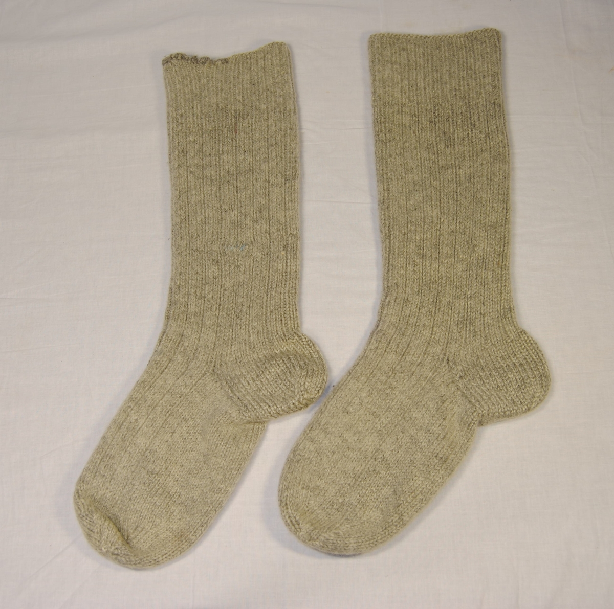 Eit par strikka raggsokkar. Noe lang i leggen. Den eine sokken (sokk A) har blitt reparert oppe langs brotet og rundt midten av leggen.