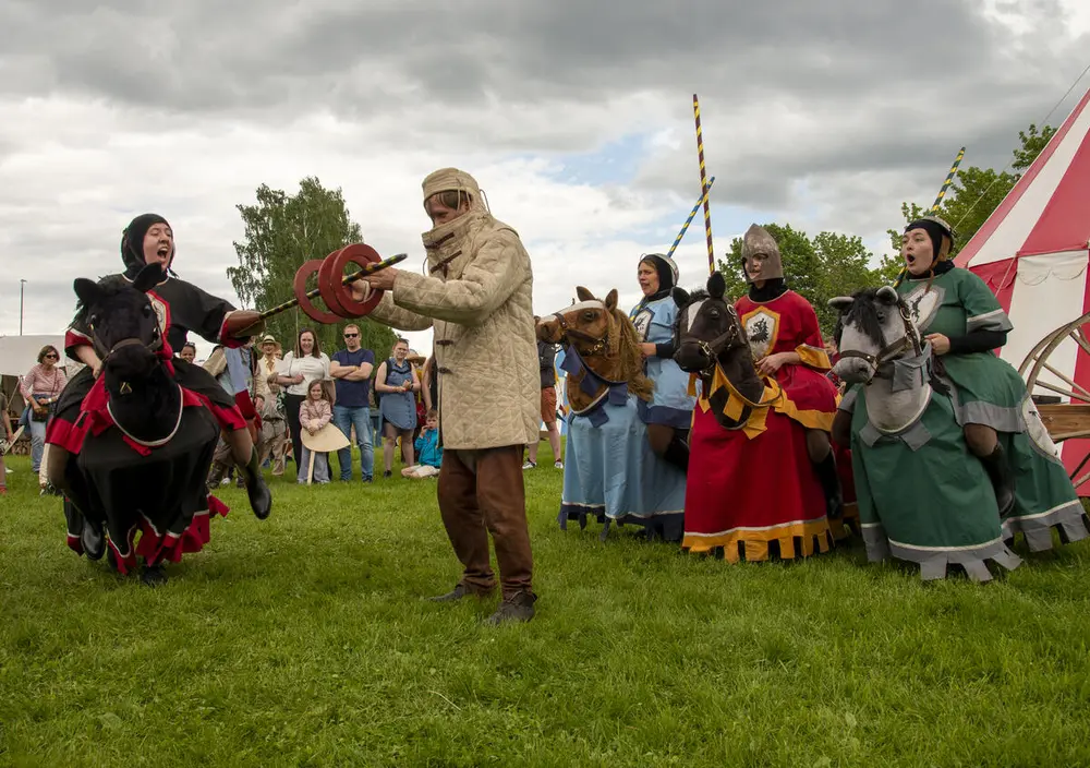 Fire minihester festet i seler på mennesker. Det ser ut som om de rir på dem. De har også med seg væpneren sin.