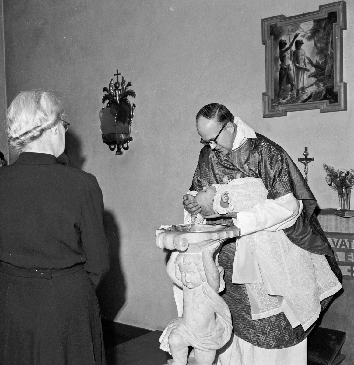Familjen Ingvar Hedberg, prästen döper barnet vid dopfunten