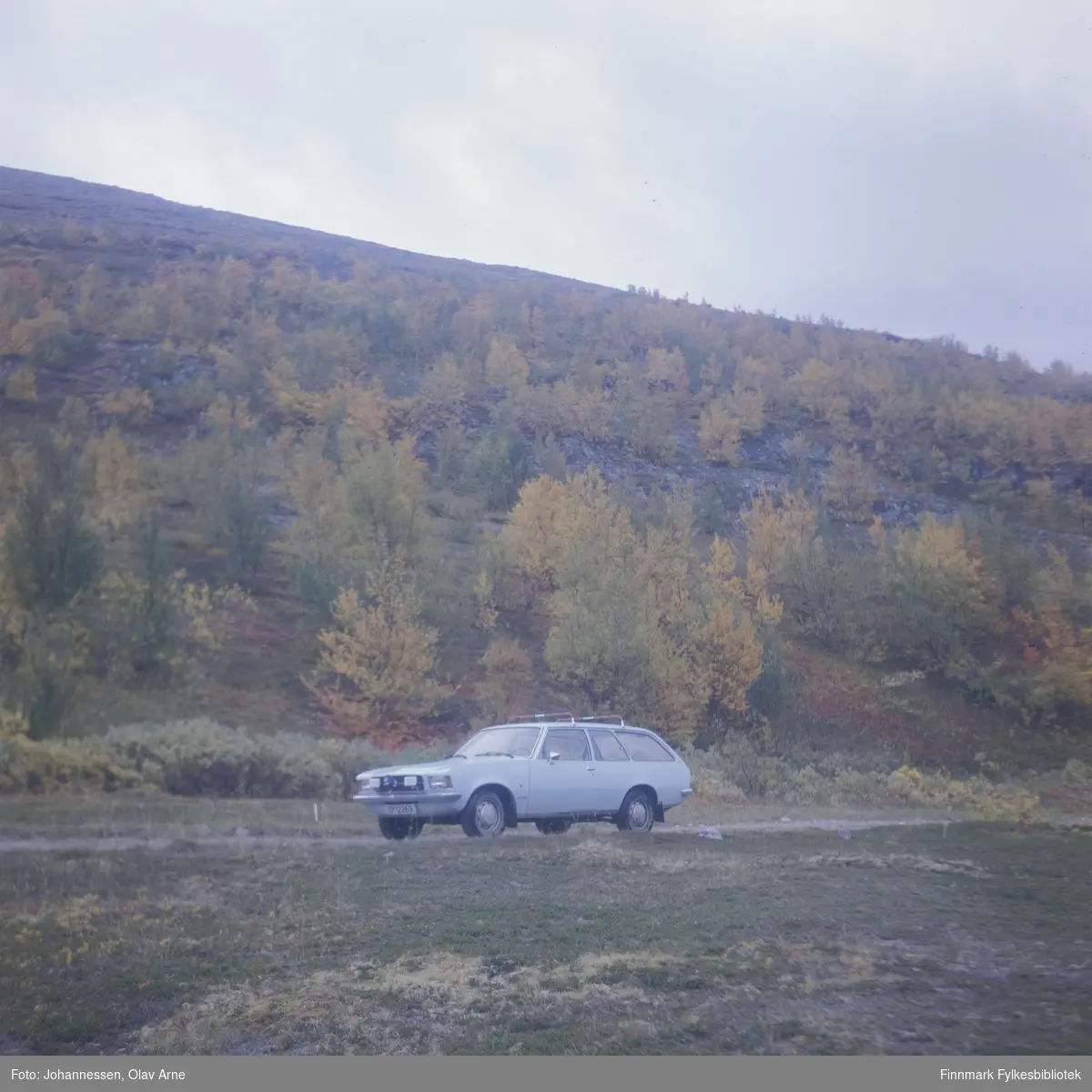 Bil står parkert på siden av grusvei, muligens i Syltefjorddalen (Finnmark)

Bilen tilhørte maleren Olav Johannessen og er en Opel Rekord 

Skiltnummer: ZP 12269