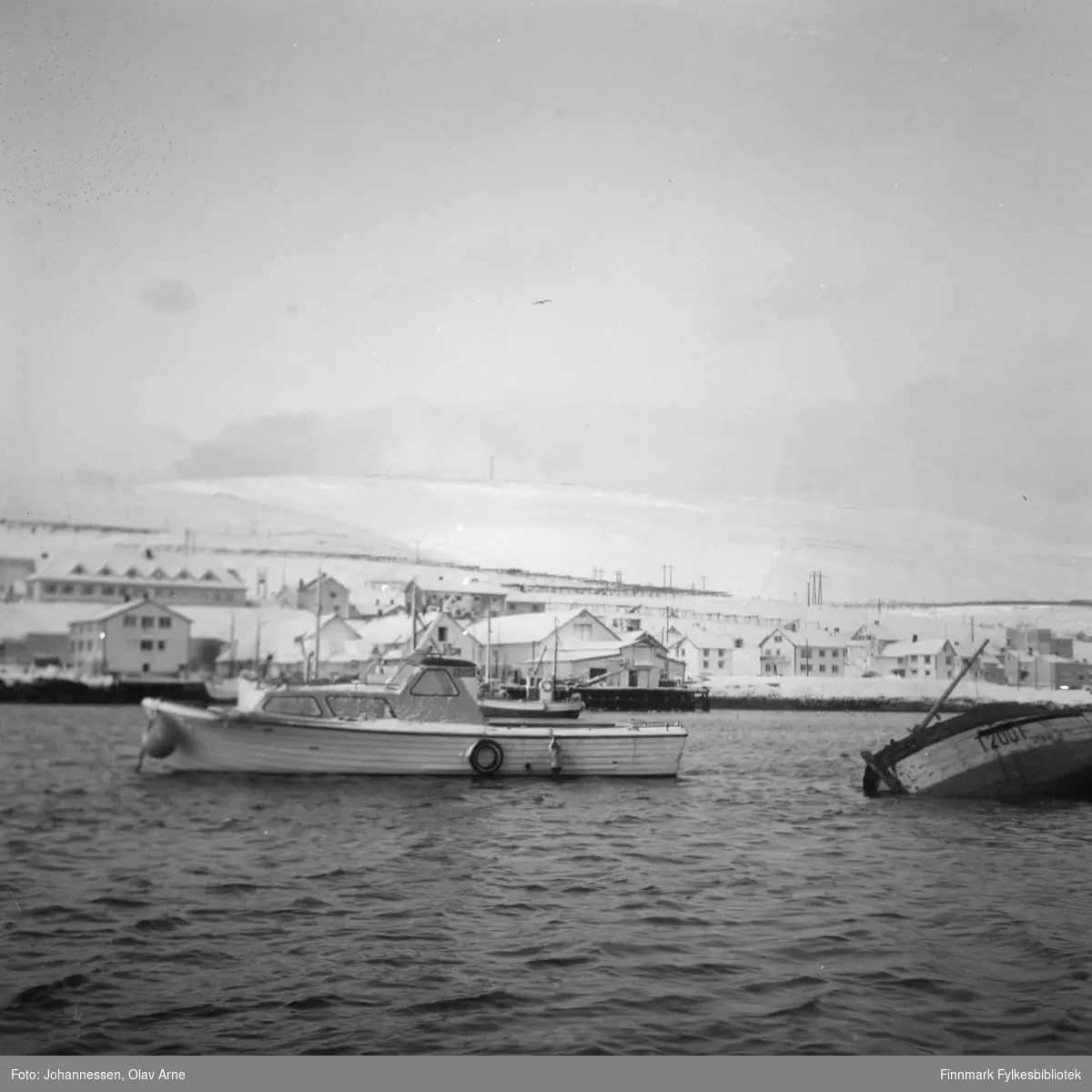 Foto av to båter. Det til høyre har havarert og har teksten  T 200 T malt på siden 

Båten til venstre tilhørte muligens fotograf Olav Johannessen i følge informant