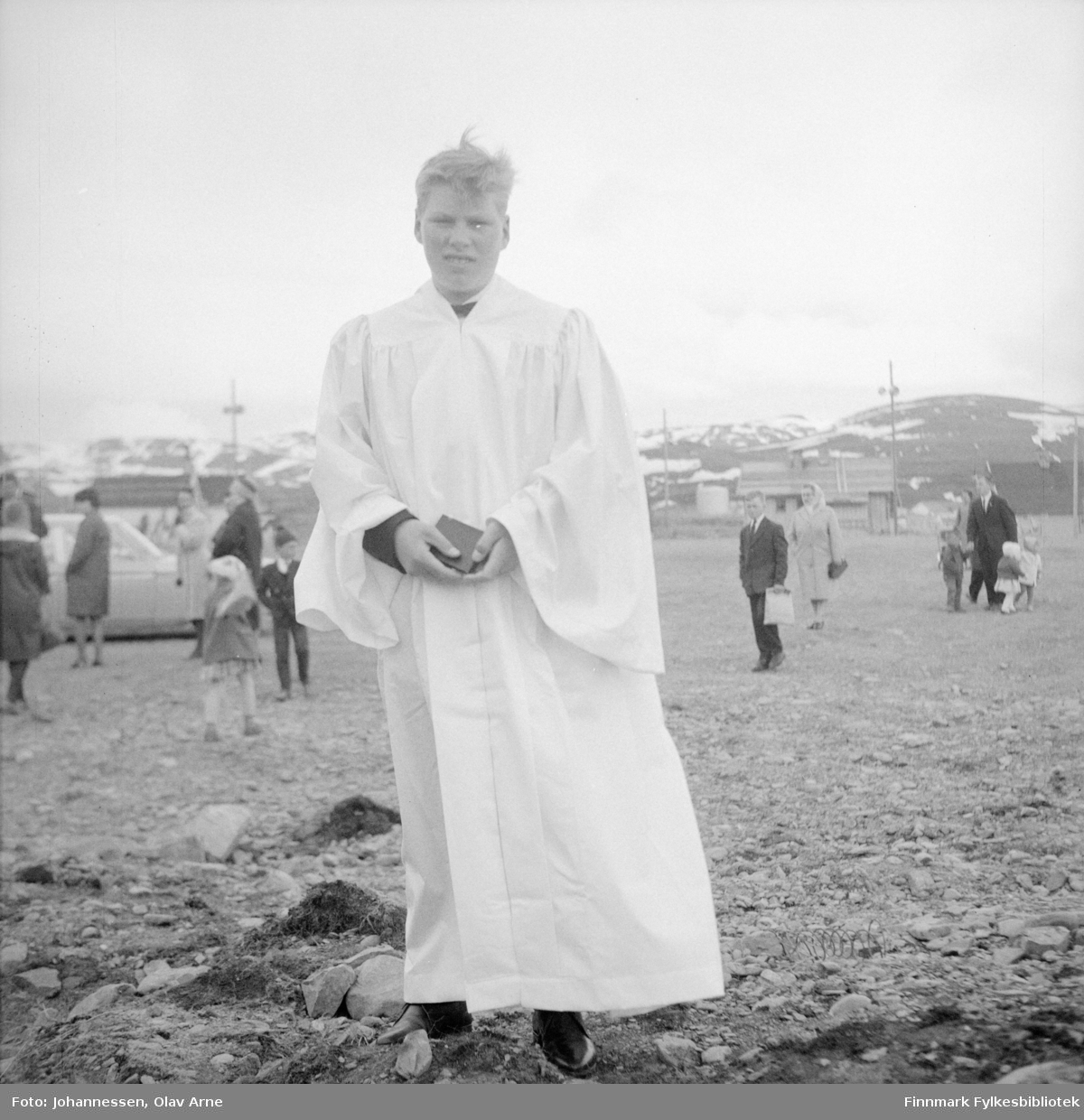 Tor Arne "Levertynna" Simonsen som konfirmant, med Båtsfjord skoleplass i bakgrunnen

Foto trolig tatt søndag 31. mai 1964 (Finnmarken annonse tirsdag 26.mai 1964)
