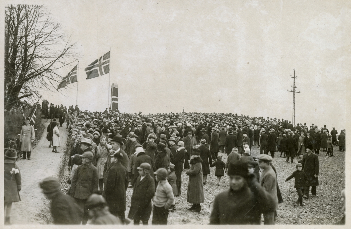 Flaggdekket bautastein med tilskuere (Bilde 1) - Roald Amundsens bautasten avsløres ved Sarpsborg - 16. des. 1928.