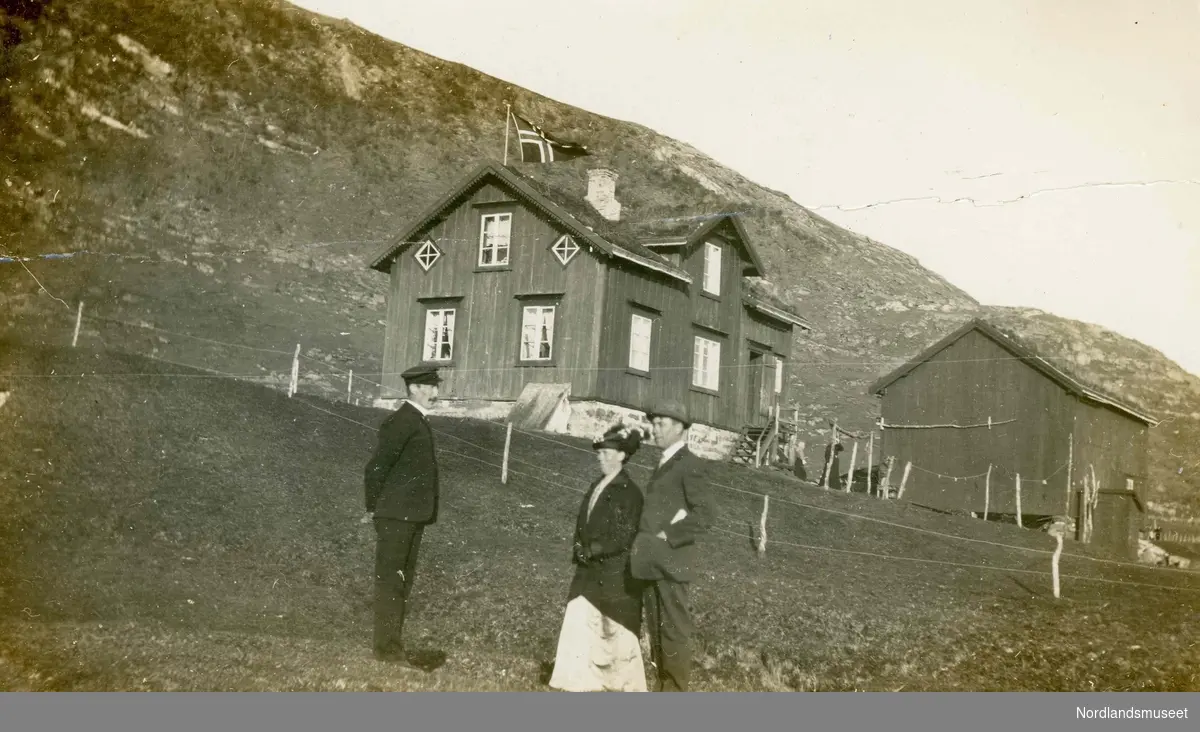 To menn og en kvinne som står utenfor et hus. Kristian Marcelius Carlsen (f. 1874) sammen med broren Olaf Bernhard Carlson (1866-1953) Olafs kone Jennie (1877-1952). Kristian og Olaf var fra Stegen på Engeløya i Steigen.