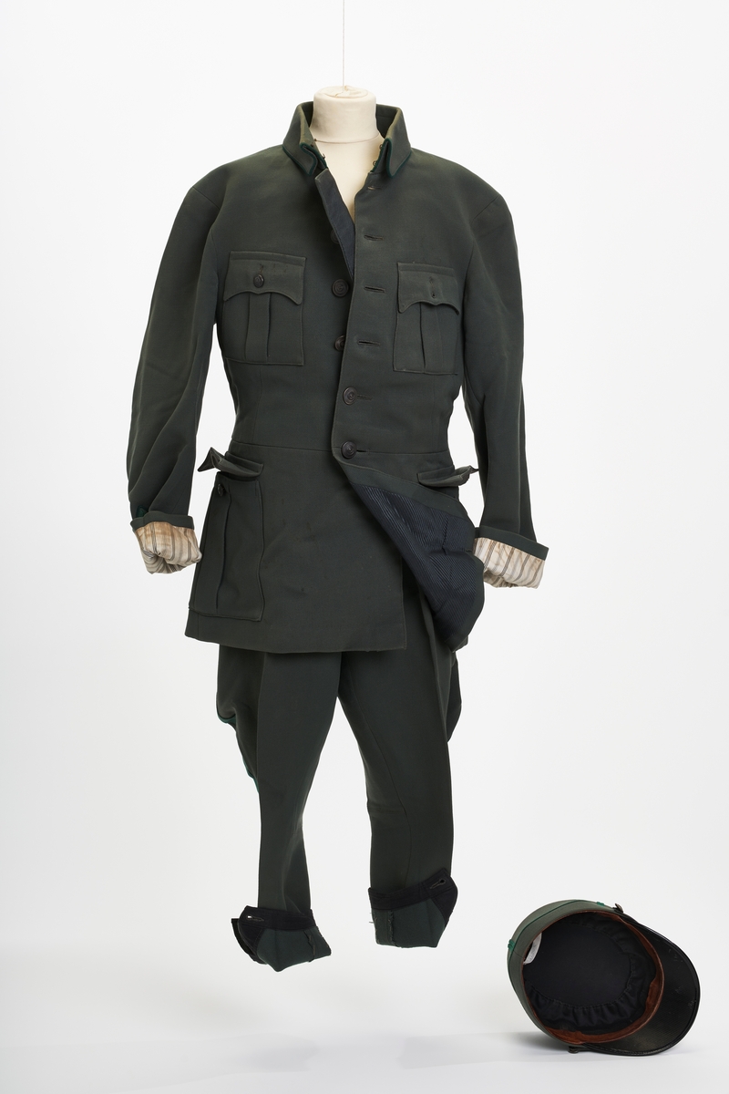 Befalsuniform bestående av jakke, bukse, lue, bandolær, to snipper og et par sporer.