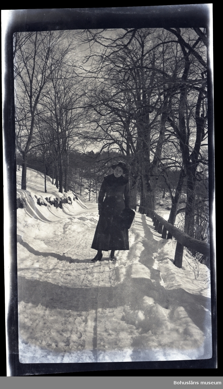 En vinterklädd person ståendes vid en snötäckt allé.