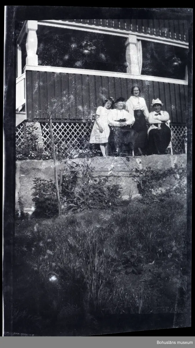 Fyra personer framför en veranda i en trädgård.