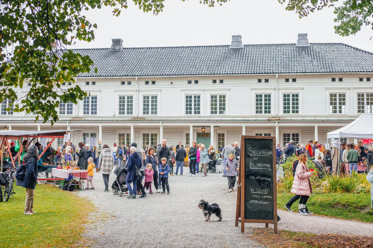 Mange mennesker på marked utenfor hovedbygningen på Linderud gård.