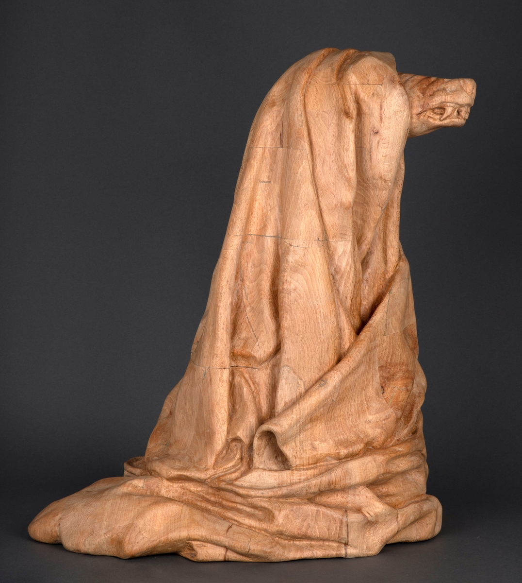 Treskulptur av en ulv foldet inn i et tøystykke.