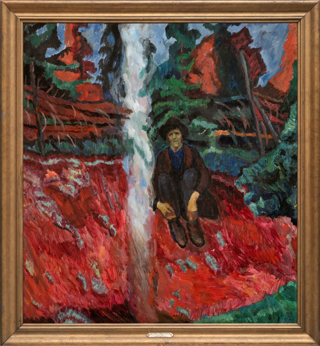 I en åpning i skogen sitter en ensom, mørkledd mann ved et bål. Røyken stiger rett til værs, gressbakken i sterk rødt. Grantrær og skigard i bakgrunnen.