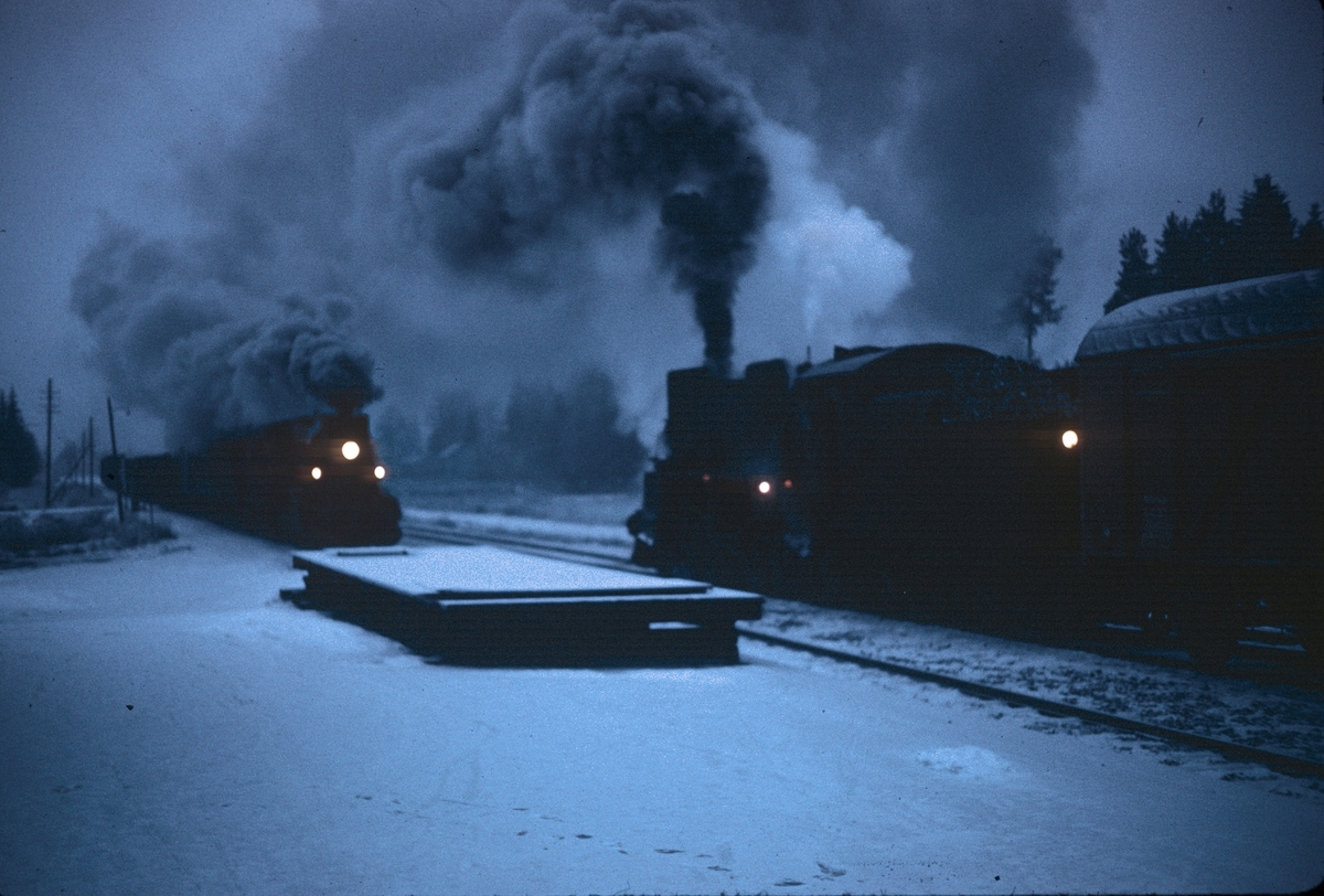 Kryssing mellom to godstog på Grinder stasjon på Solørbanen. Til venstre damplokomotiv type 27a, til høyre type 26c