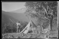 Mann på teltur med utsikt mot Gaustatoppen. Pyramidetelt slå