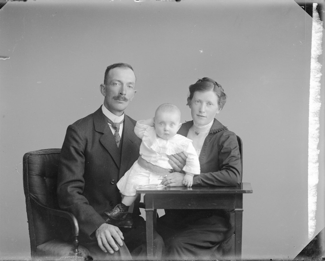 En man och en kvinna med ett litet barn som sitter på ett bord mellan dem.