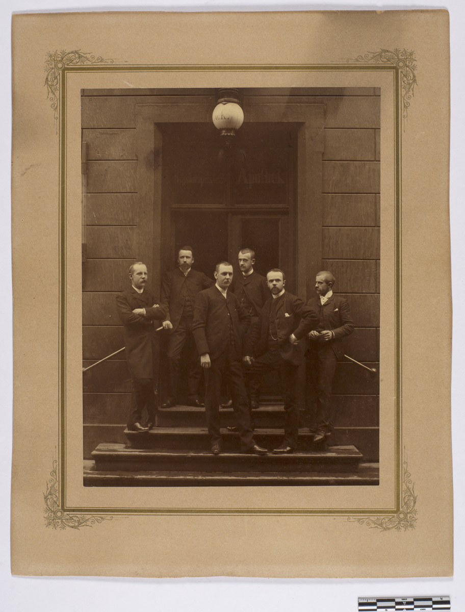 Gruppefoto med fra venstre Frølich, Grøntoft, Linaae, Holm, Dessen og Herdal på trappen utenfor Rikshospitalets apotek, 1892.
Trolig farmasøytisk personale ansatt i dette året.