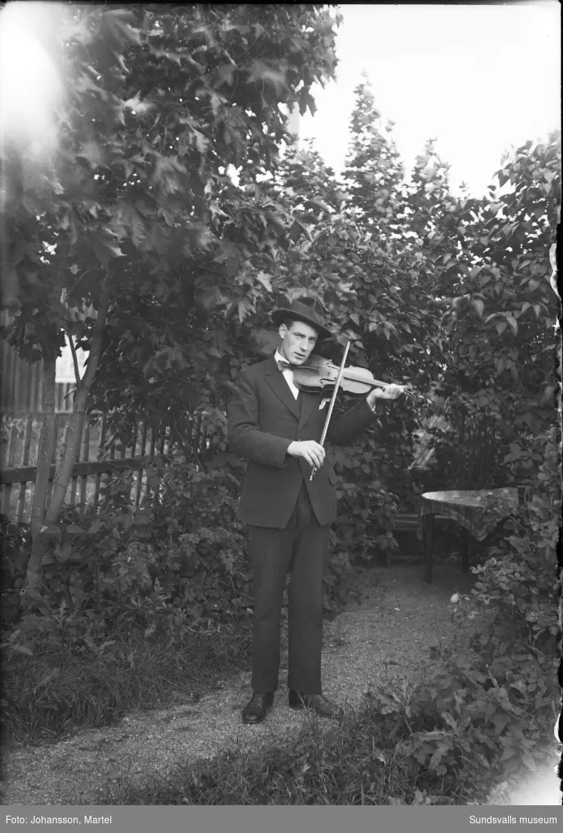 Sigfrid Hjärpe, Sörfors, spelar fiol i bersån i en trädgård.