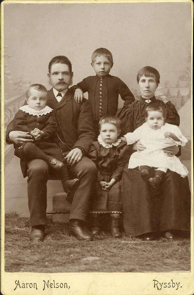 En okänd familj med fyra barn hos fotografen.
Helfigur. Ateljéfoto.