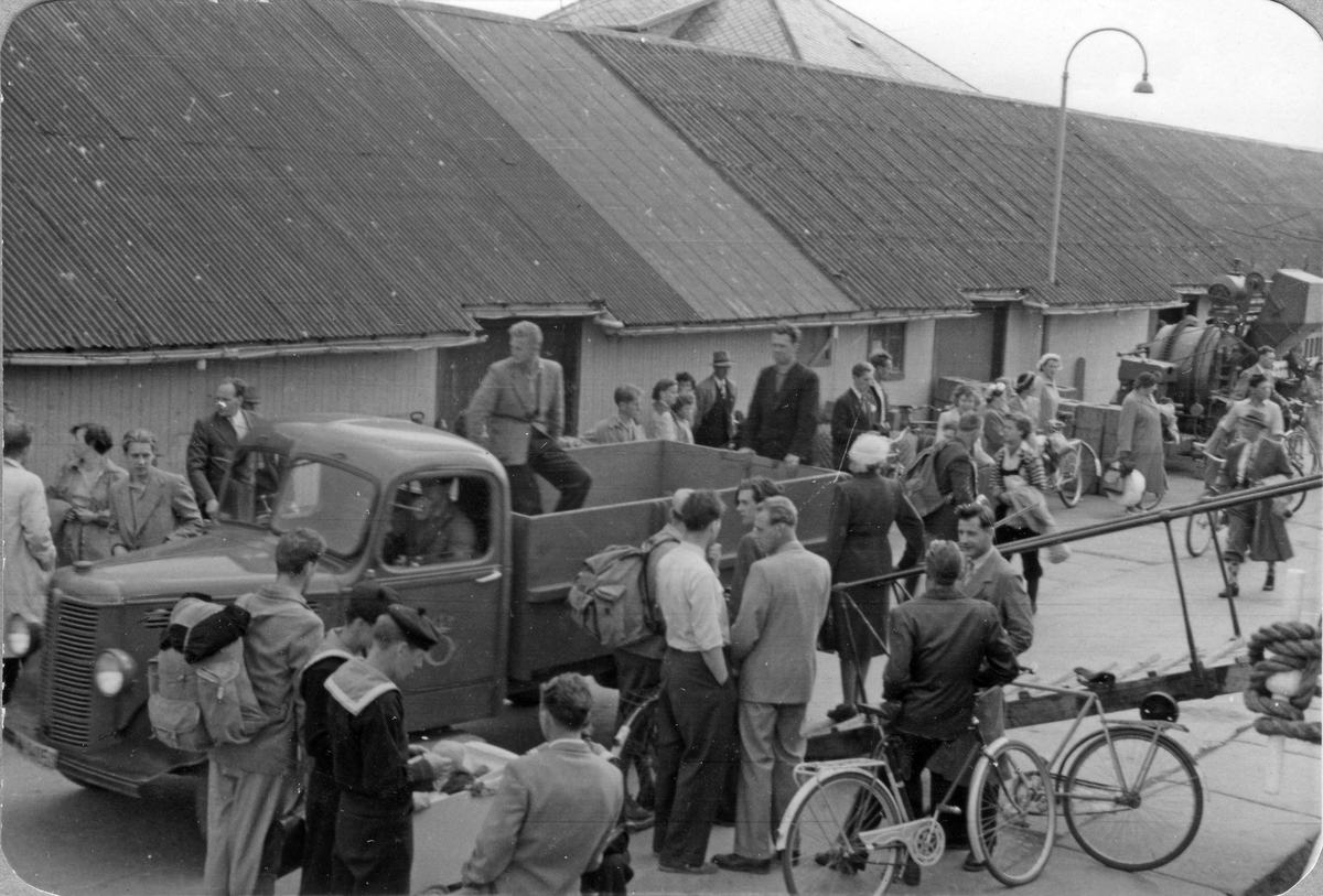 Folkeliv på kaia i Bodø tidlig på 1950-tallet, med "kaiskuran" og de ulike hurtigruteekspedisjonenen i bakgrunnen.