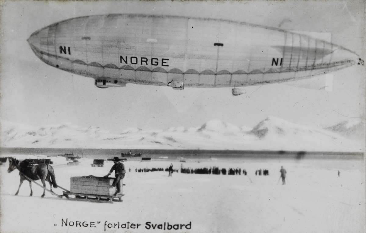 Dias. Luftskipet Norge svever over et snødekket landskap på Svalbard. Under skipet står en mann bak en slede med en stor kasse trukket av en hest.