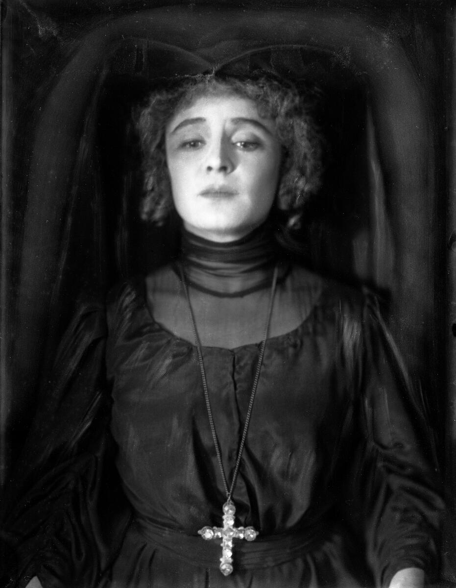 Portrett av skuespilleren og sceneinstruktøren Gerda Ring. Hun poserer i en svart kjole og en vid hodebekledning. På brystet bærer hun et korskjede.