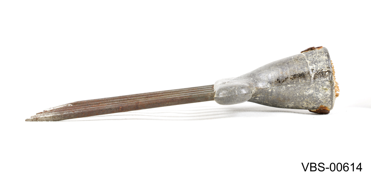 Fiskestikke i form av en gaffel eller harpun. Hodet av tinn har fire og tynne spiss med en mothaker hver som fiskekroker på enden.
I den andre enden er det en resten av trehåndtaket (mangler) festet med to jernspiker .