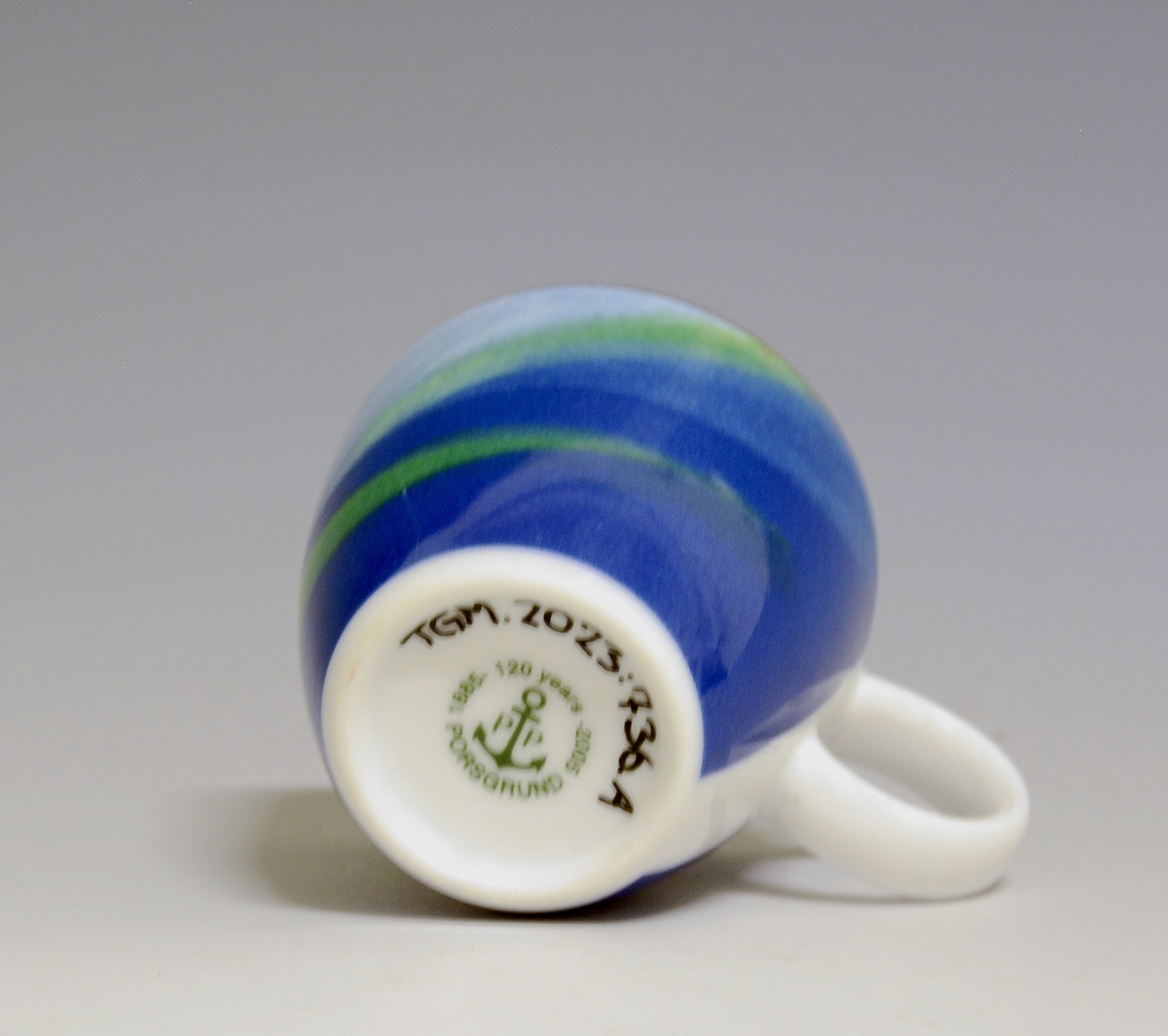 Espressokopp av porselen, med rund hank. Heldekkende dekor i grønt og blåtoner. 
Modell: Barista, forgitt av Poul Jensen.
Dekor: Blue Java