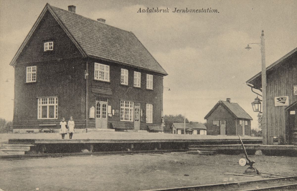 Postkort, Løten, Ådalsbruk stasjon, 2 jenter i kjole på perrongen, sporveksler, pakkhus,