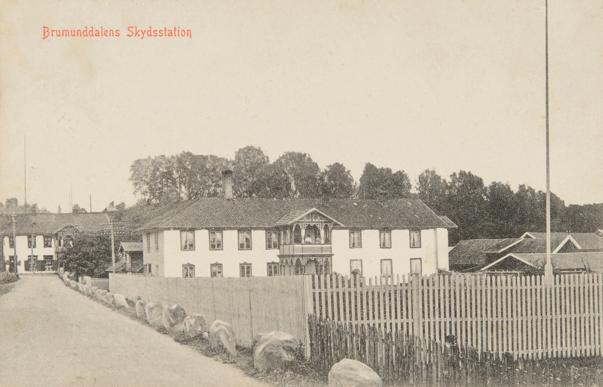 Postkort, Ringsaker, Brumunddal Hotell etablert i 1895, skysstasjon i Øverbakken. Furnesvegen, stakitt, Heimdal i enden av gata,