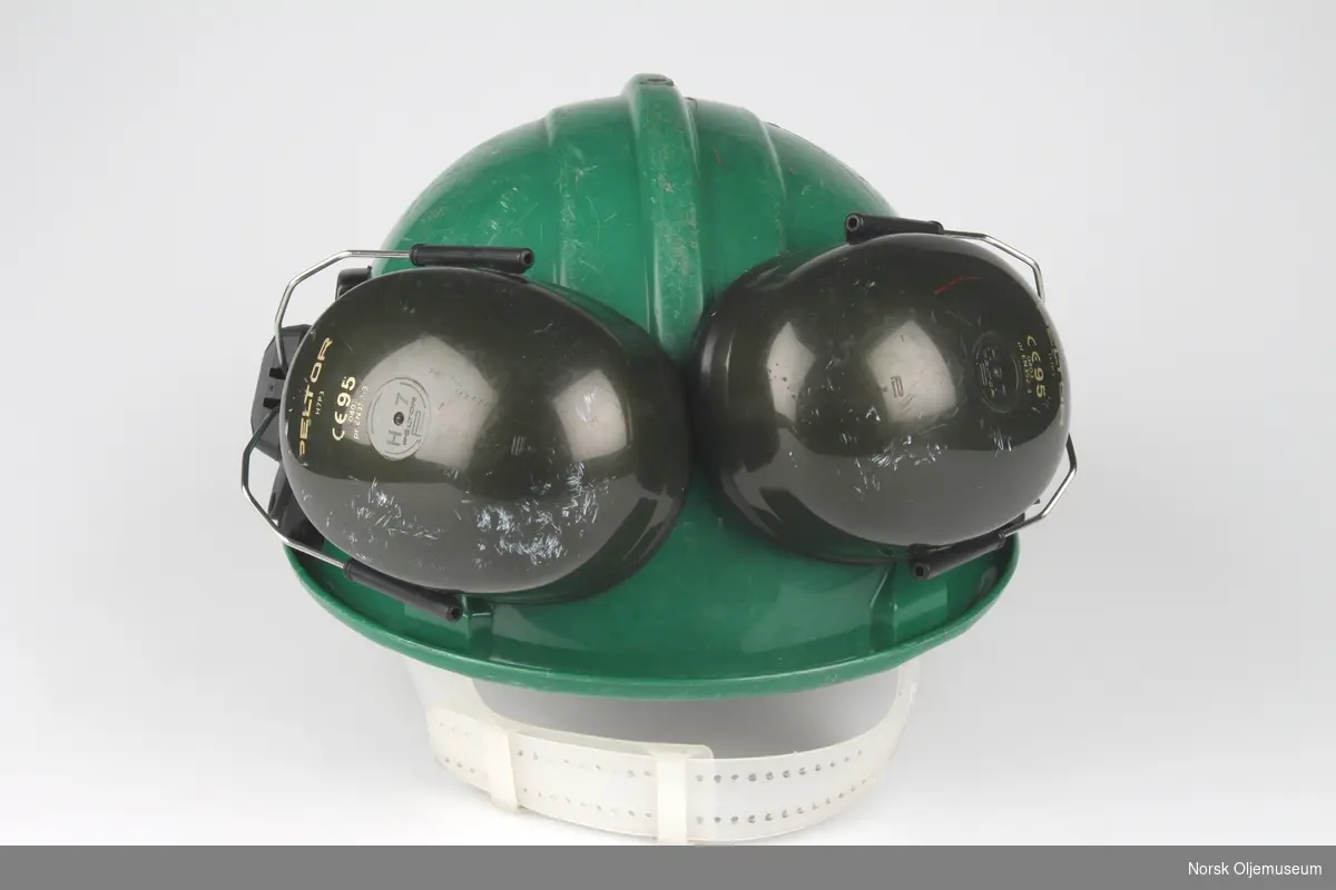Grønn vernehjelm med hørselsvern. Foran på hjelmen er det et klistremerke med logo til Flopetrol Johnston Schlumberger.