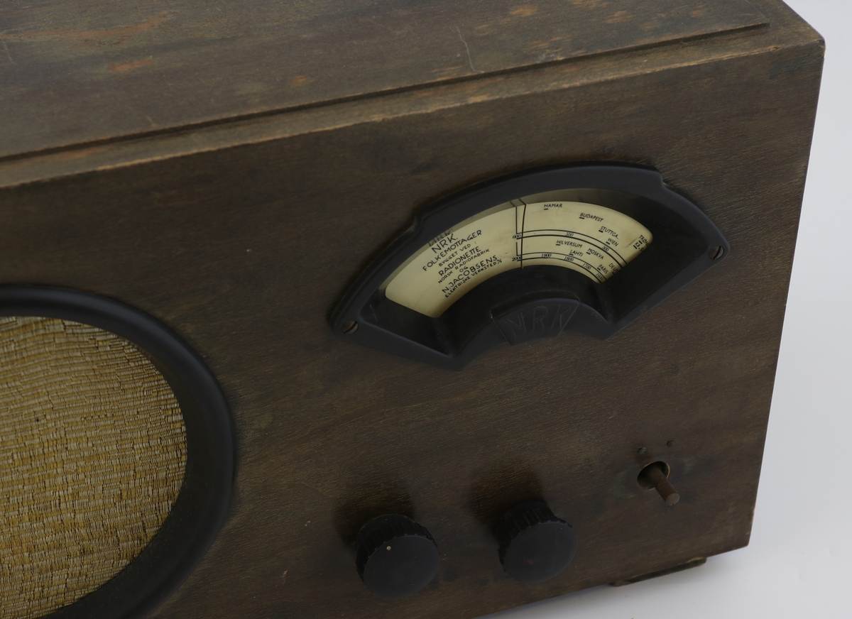 Brun rektangulær radio av tre med høyttaler, display og vridere for valg av stasjon.