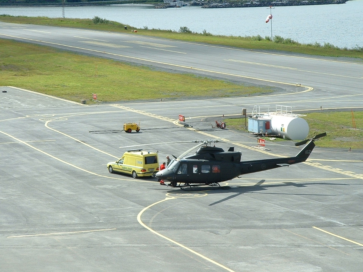 Et helikoper, Bell 412 fra Luftforsvaret, på Narvik flyplas med en ambulanse ved siden av.