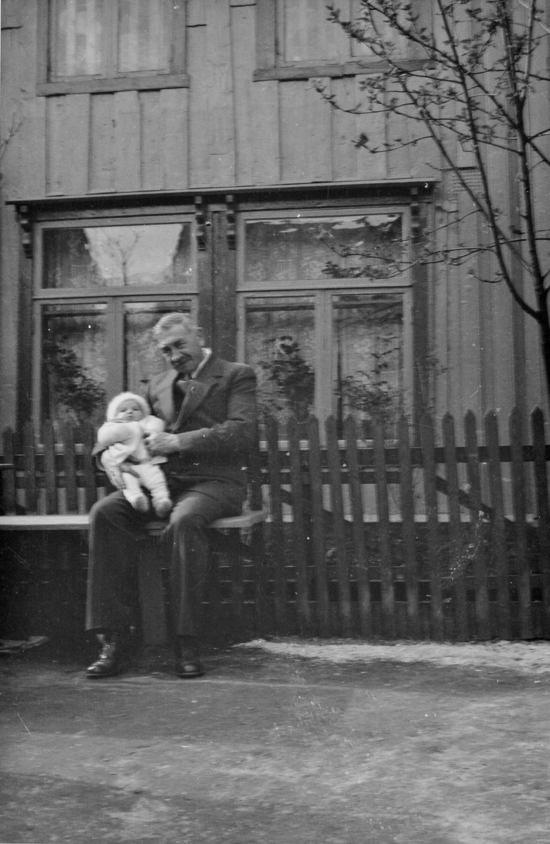 Daniel Caplan med barnebarn Harry Caplan sitter på en benk foran et hus