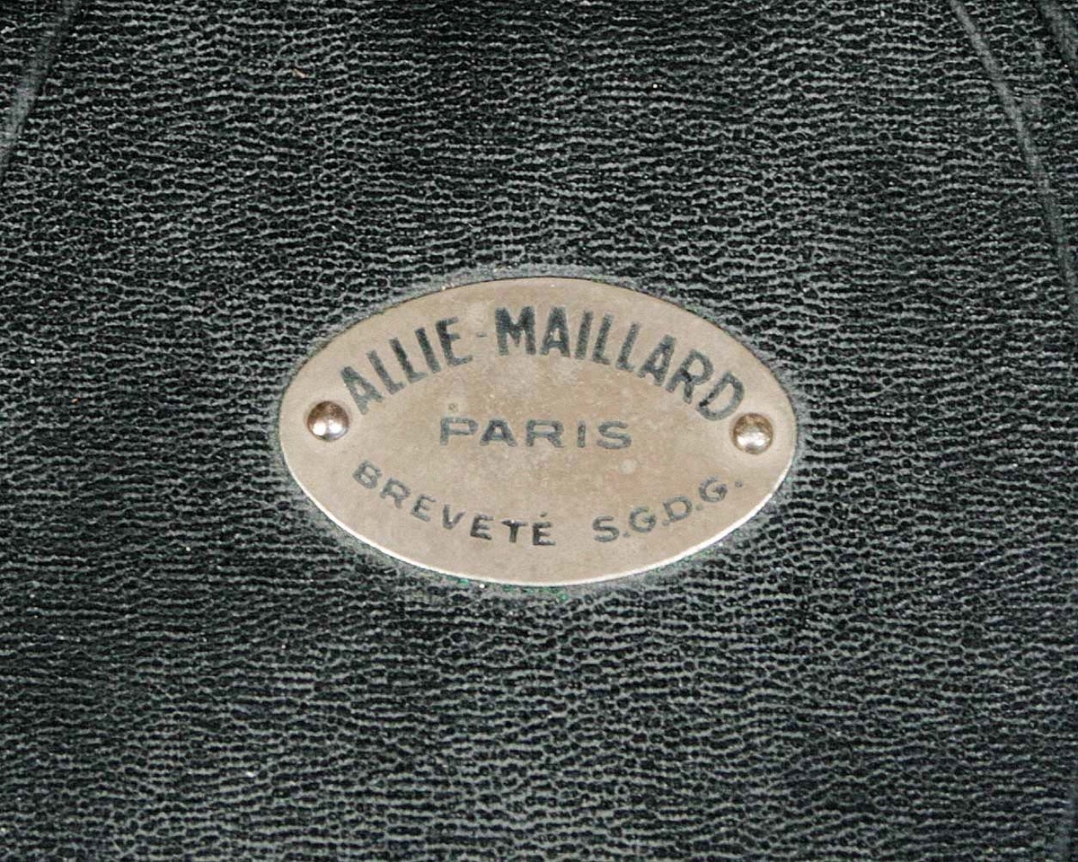 Conformateur (hattformare). Tillverkad i Paris, av Allie-Maillard omkring 1890-1900. Med justerbara stavar för inställning. Medföljer två mässingsband. Består av 5 delar. Förvaras i en gråmålad trälåda med lock.

Användes på en kunds huvud, för att mäta storlek och form. Användes av högkvalitativa hatt-tillverkare.

Funktion: Mäta storlek och form på huvudet