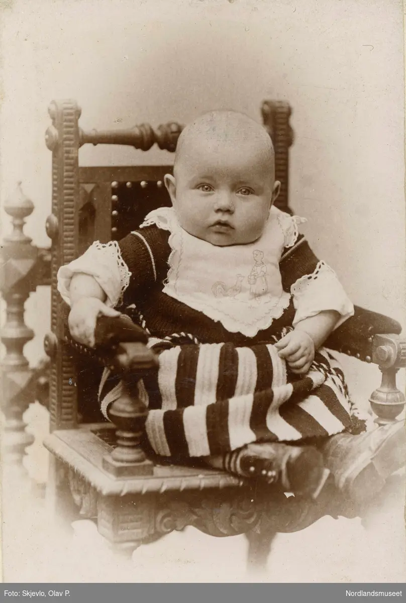 Portrett av et lite barn som sitter på en stol.