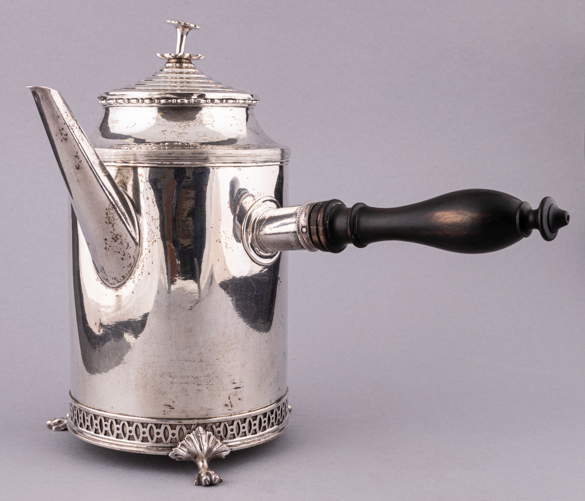 Gustaviansk kaffekanna i silver, med svarvat svart trähandtag och tre fyrtåiga fötter.