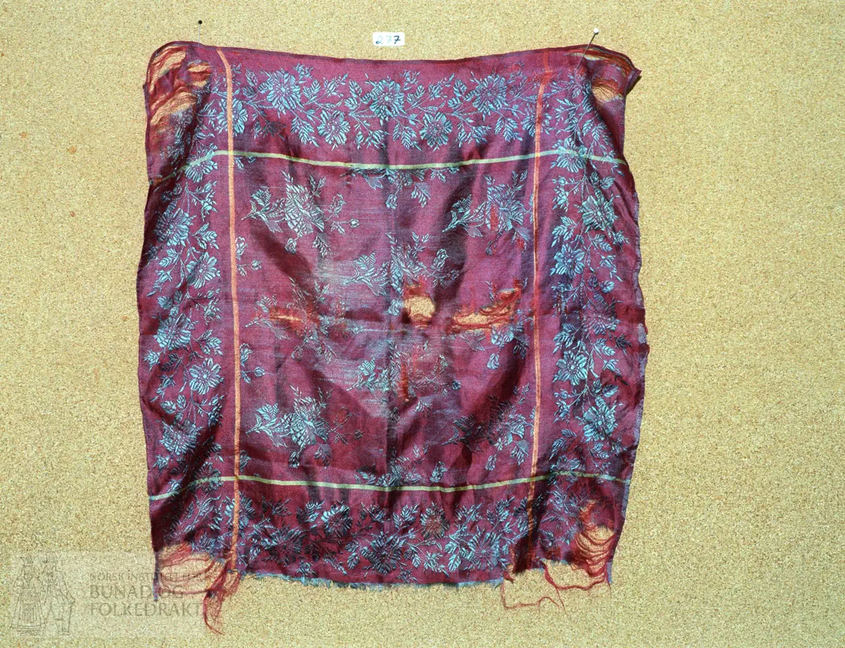 Damaskvoven silke i blåraudt, blågrønt og gult. Storleik:  50 x 49,5 cm.