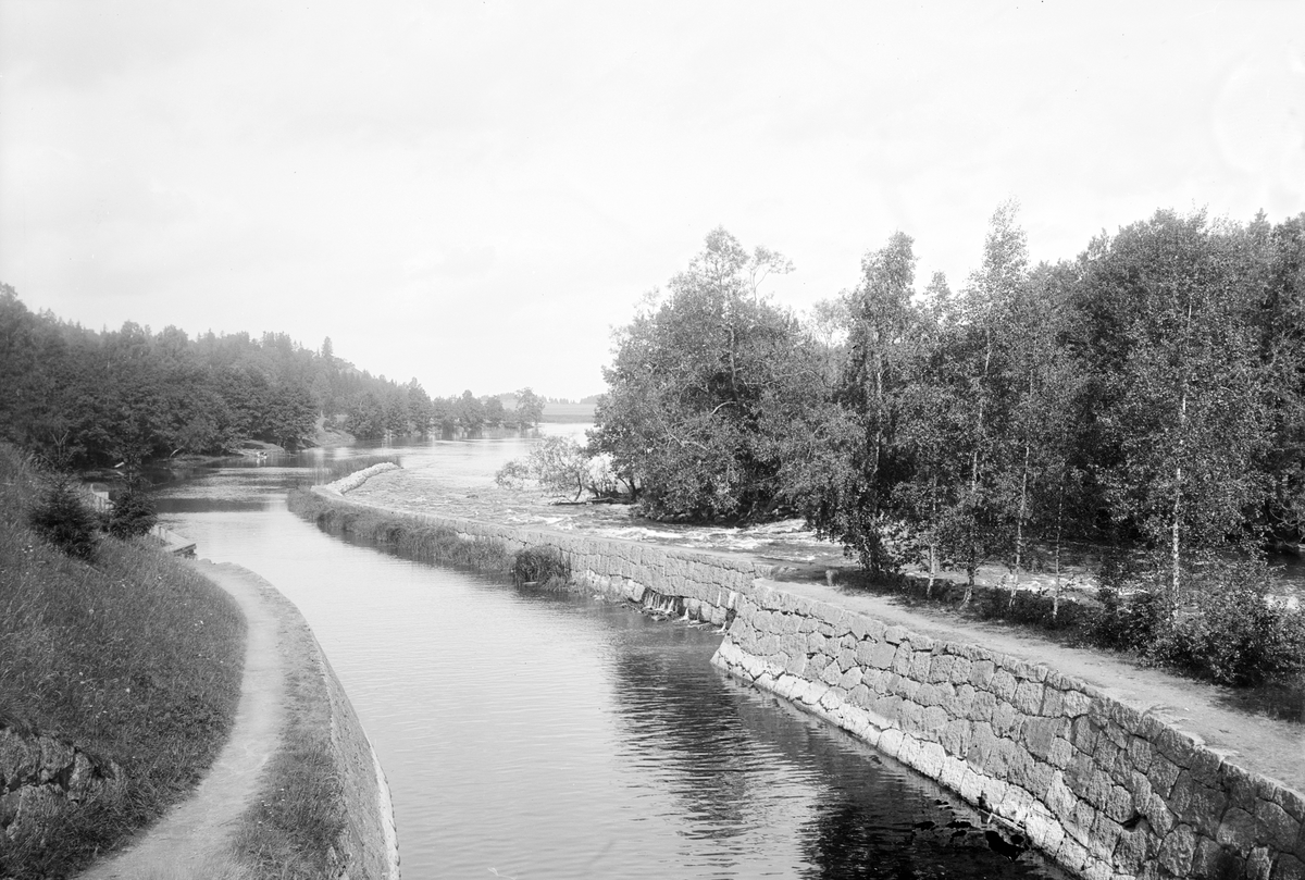 Vy från Hackefors sluss med utblick mot norr. Slussen tillkom i slutet av 1860-talet som del i den år 1871 invigda Kinda kanal. Stenpiren delar effektivt den stilla kanalen från Stångåns mer otämda flöde. Bilden kan dateras till perioden 1896-99.