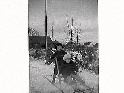 Två barn från Vita Bandets barnhem i Varberg åker spark i snön.