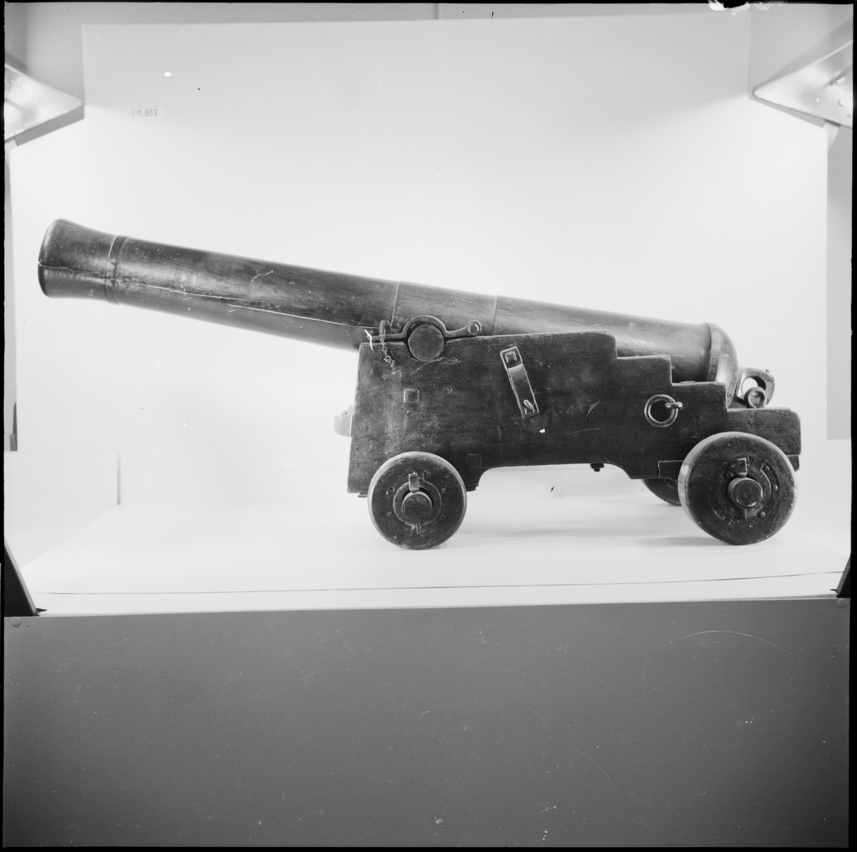 Kanonmodell: 4-rull låda med kanon, av Chapmans modell. Lådan av trä, kanon och beslag av järn. Tillbehör: 1 st ställhult. Lavetten L = 650 mm B = 435 mm H = 315 mm.