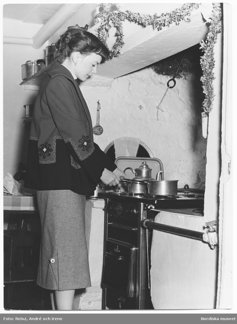En ung kvinna i köket vid spisen.