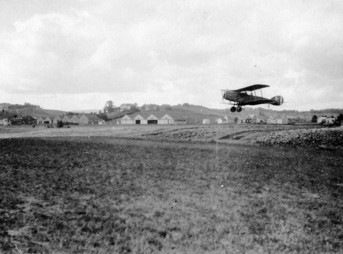 Øvelse for vernepliktige i den søndenfjeldske flyveavdleings sommeren 1923. Et britisk toseters kamp- og rekognoseringsfly av typen Bristol Fighter inn for landing. Hærens Flyvevesen brukte disse flyene i tiden 1921 - 1933.