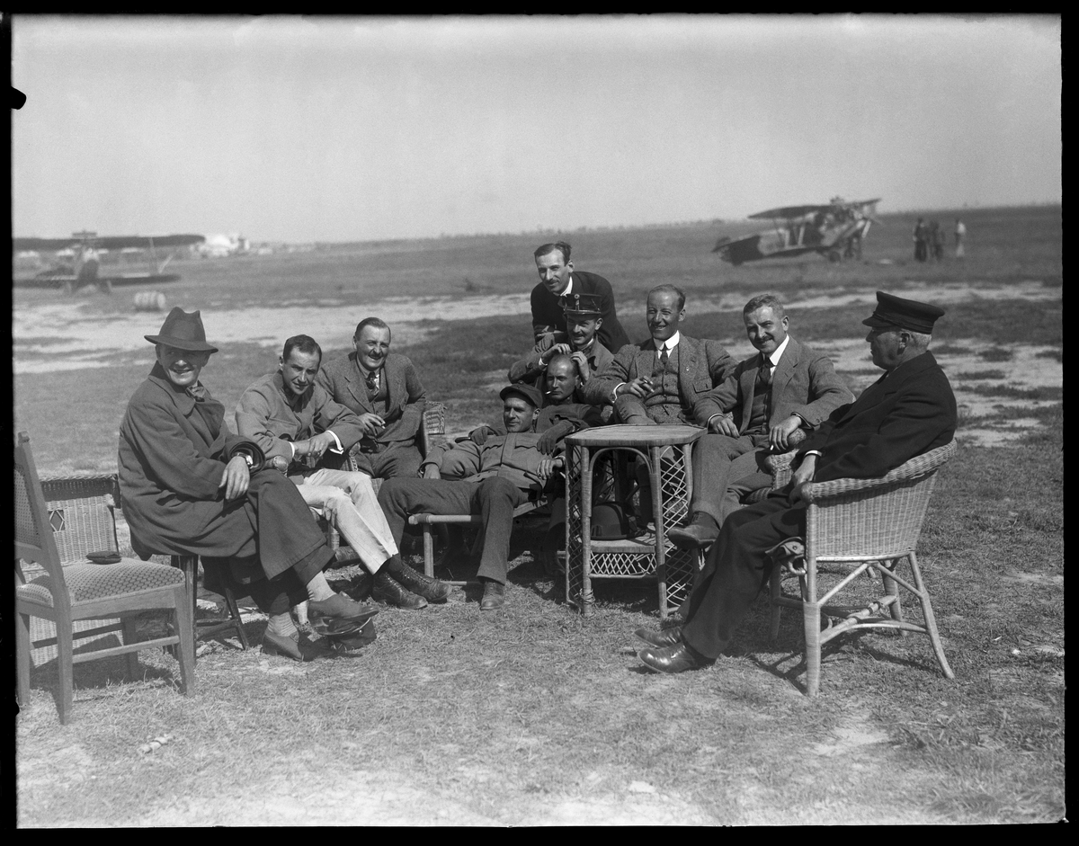En samling om 10 män sitter i stolar i utkanten av ett flygfält i Österrike-Ungern under första världskriget. Tredje mannen från höger är Edmund Sparmann. I bakgrunden står militära flygplan.