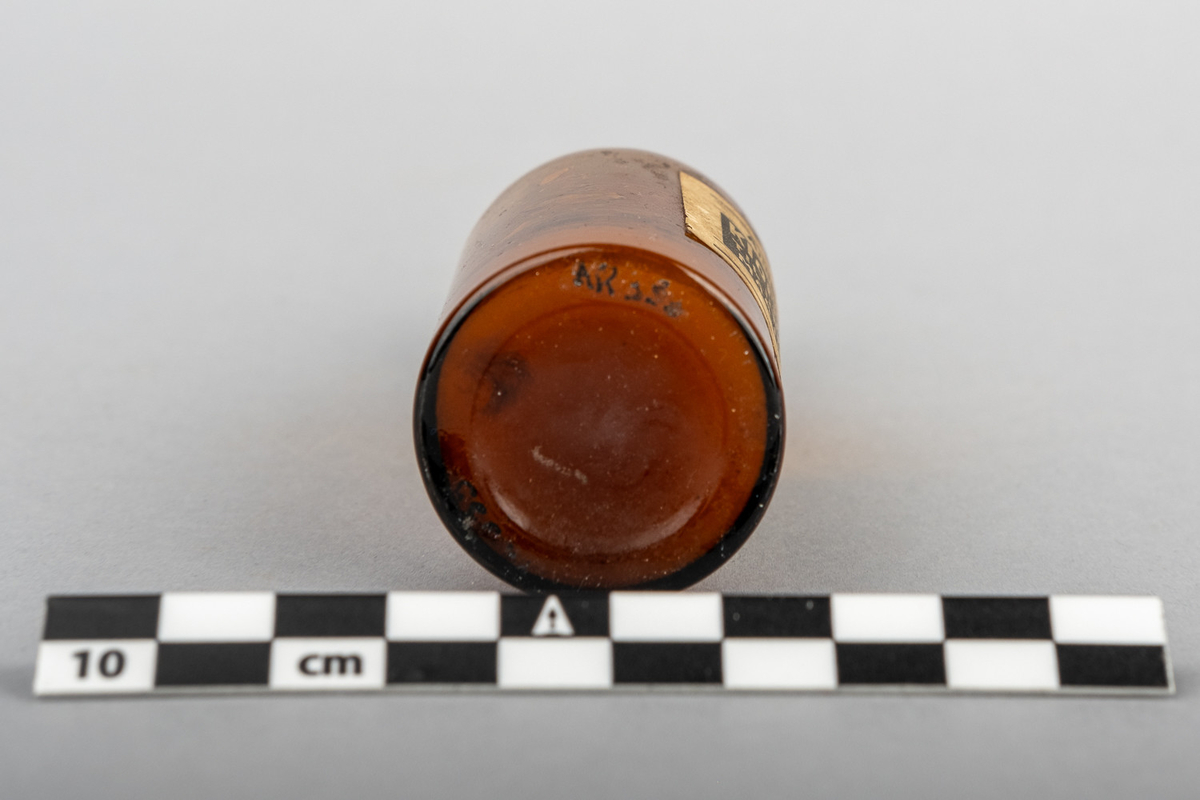Medisinflaske, brun med kork og innhold. Merkelapp som identifiserer innhold som kloroform. 