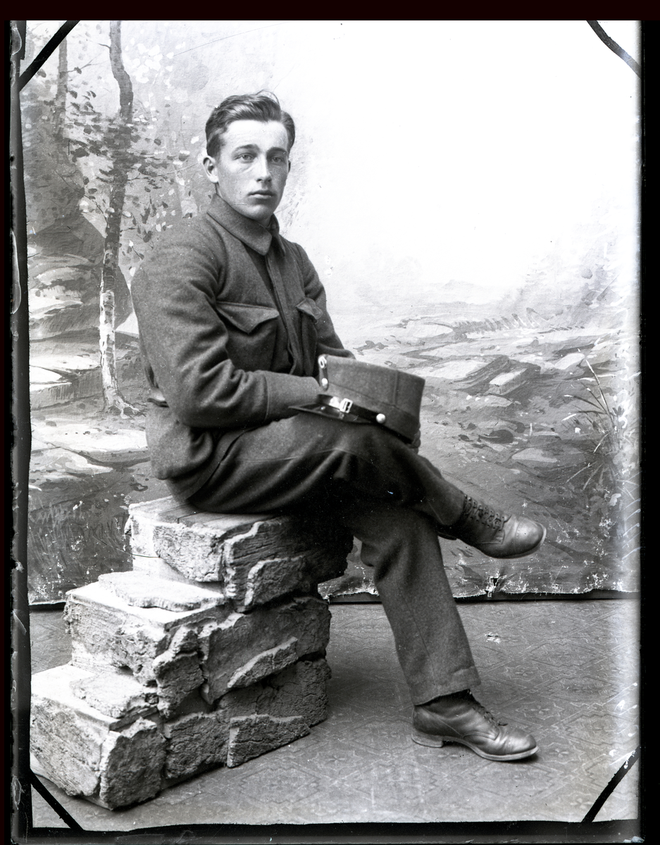 Atelierfoto. Helfigur. En soldat sitter.
Skrevet på negativet: Trygve Kulsvehagen 1927, se bilde: GM_MG.00782_1.
Sannsynligvis Trygve Kulsvehagen (1906-1934), Ringsaker.